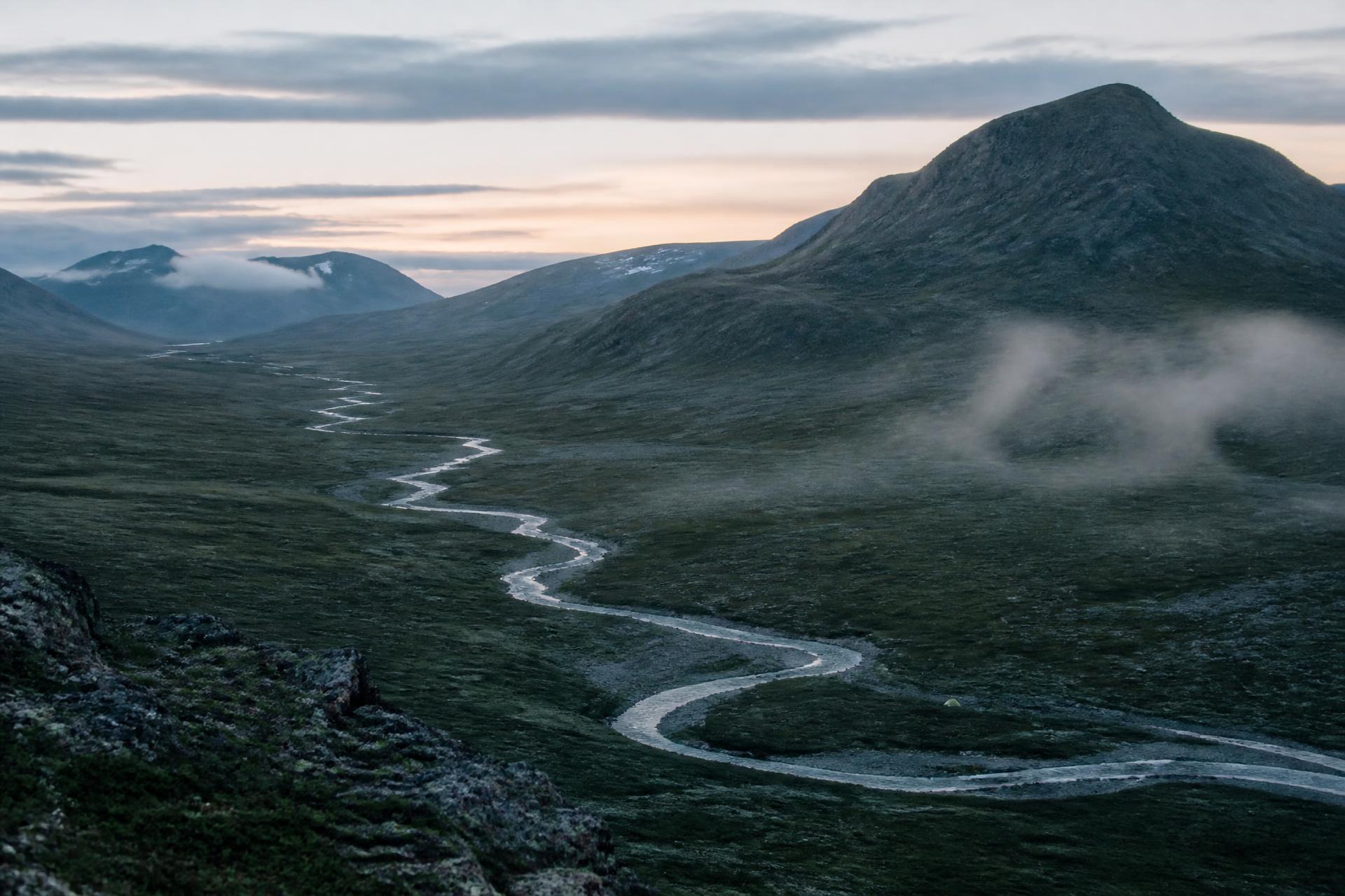 Vast mountain wilderness near Ottfjäll in Jämtland, Sweden, with a river and a single tiny tent